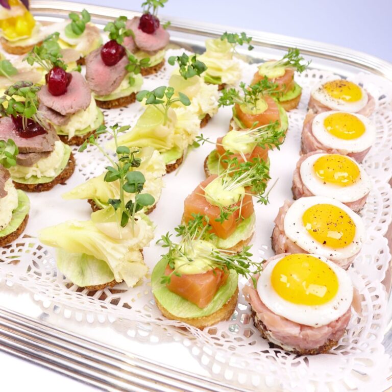 Canape Häppchen auf einem silber Tablett. Ei, Lachs, Käse und Roastbeef. Insgesamt 22 Häppchen sind zu sehen.