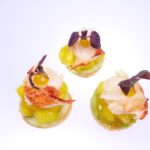 Drei Canape Häppchen vor weißem Hintergrund. Fisch mit Salat und Mango.